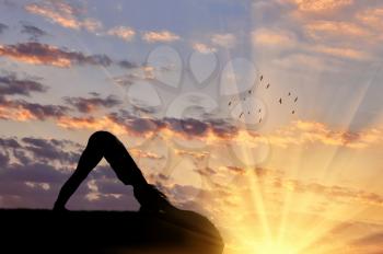 Concept of meditation and relaxation. Silhouette of a girl practicing yoga exercise on the sunset background