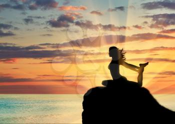 Concept of meditation and relaxation. Silhouette of a girl practicing yoga class on a background of sea sunset