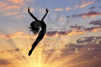 Concept of happiness and freedom. Silhouette of happy woman jumping at sunset