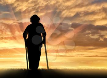 Silhouette of an old woman on crutches outdoors. Concept of disability and old age