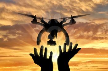 Silhouette drones take off from human hands on a sunset background
