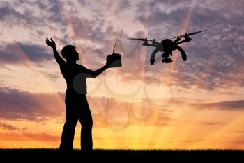 Silhouette of a flying drone, and a man with a remote control at sunset. Concept quadrocopters
