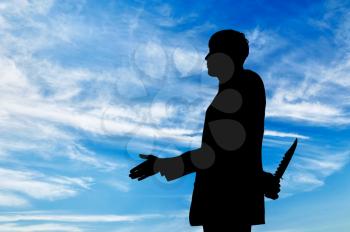 Concept of business betrayal. Silhouette of a businessman shaking hands and holding a knife behind his back