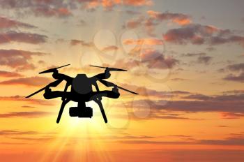 Silhouette of a flying drone on sunset background