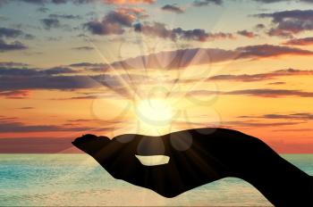 Concept of emotions and feelings. Silhouette of a hand holding the sun at sunset