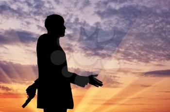Concept of business betrayal. Silhouette of a businessman shaking hands and holding a gun behind his back