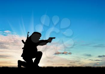Concept of terrorism. Silhouette of a terrorist with a rifle on a background of sunset 