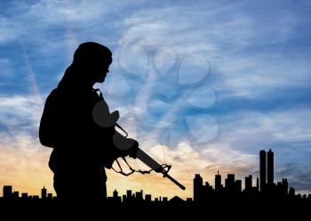 Concept of terrorism. Silhouette of a terrorist on city background at sunset