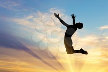 Concept of happiness and freedom. Silhouette happy man jumping on a sunset background