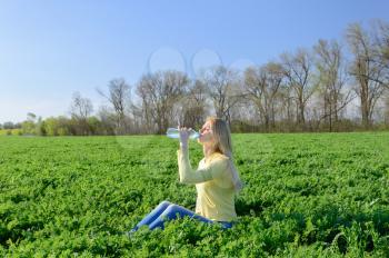  Concept of thirst. Young woman relaxing drinks water from a plastic bottle