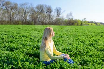 Concept of outdoor fun. Young woman resting on the green grass in the meadow