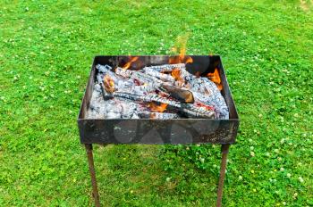 Brazier with burning coals on lawn grass