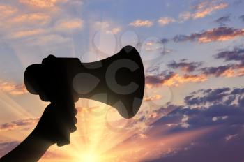 Megaphone. The loudspeaker in his hand on a sunset background