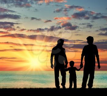 ?oncept of gay parents. Silhouette of parents of gays and baby boy walking near the sea at sunset