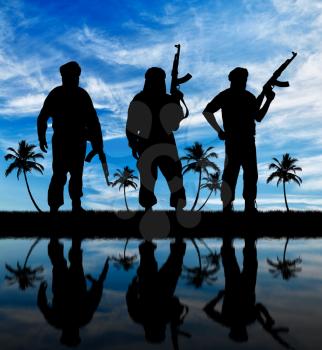 Silhouette of three terrorists with a weapon against a background of blue sky and palm trees reflecting in the water