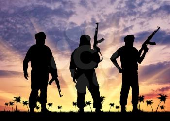 Silhouette of three terrorists with a weapon against a background of sunset and palm trees