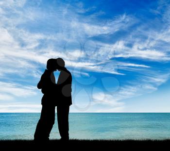 Concept of gay people. Silhouette of two gay men kissing at the sea during the day