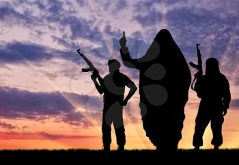 Silhouette of three terrorists with weapons dictate their terms at sunset