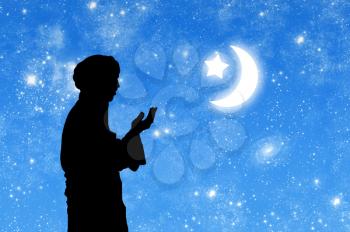 Concept of Islamic culture. Silhouette of man praying on the background of the starry sky and the moon