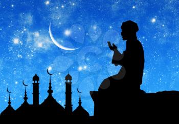?oncept of the Islamic religion. Silhouette of the town hall and praying men on the background of the starry sky and the moon
