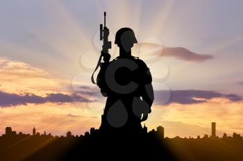 Silhouette of a terrorist with a weapon against a background of the urban landscape at sunset. The concept of terrorism and war