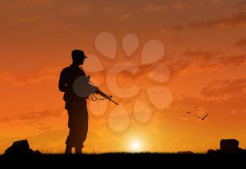 Silhouette of a terrorist with a weapon at sunset. The concept of terrorism and war