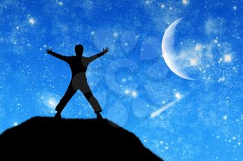 Concept of success. Silhouette of a happy man at the top of the mountain against the sky in the moonlight with stars