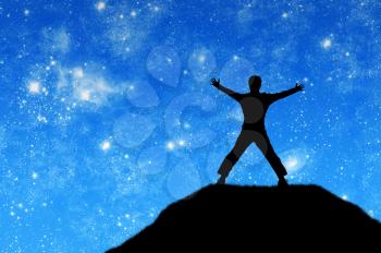 Concept of success. Silhouette of a happy man on the mountain top against the sky with stars