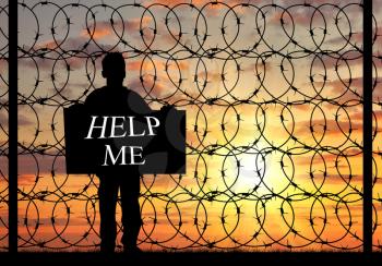 Concept of refugee. Silhouette of a refugee with a poster asking for help against the sunset