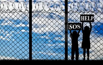 Concept of refugee. Silhouette of refugee children with placards in their hands asking for help near the fence