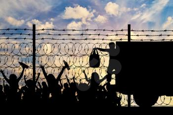 Concept of the refugees. Silhouette of humanitarian assistance to refugees near the fence with barbed wire