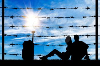 Concept of refugee. Silhouette starving refugee families with a bag near the fence of barbed wire