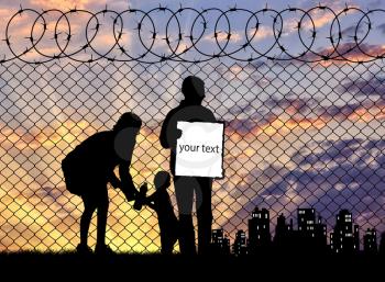 Concept of the refugees. Silhouette of a refugee family with a child near the fence at sunset with a poster for your text