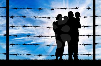 Concept of refugee. Silhouette of a family with children of refugees and fence with barbed wire