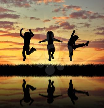 ?oncept of happiness. Silhouette happy children jumping at sunset and reflection in water