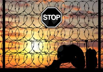 Concept of refugee. Silhouette Despair refugee woman near the fence of barbed wire