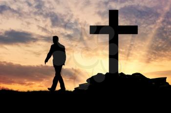 ?oncept of an atheist. Silhouette of a man on the background of the cross at sunset