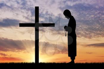 Concept of religion. Silhouette of priest and cross on a background of beautiful sky