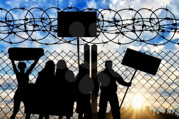 The concept of the refugees. Silhouette protesters refugees near the fence with barbed wire expressing discontent