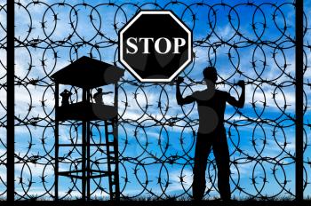  Concept of refugee. Silhouette of a refugee near the fence with barbed wire and watch tower