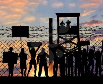 Concept of security. Silhouette refugees protesting outside the metal fence with barbed wire on the background of night sky