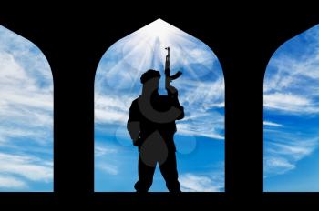 Concept of terrorism. Silhouette of a terrorist with a gun in a building