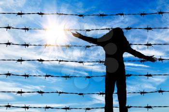 Concept of refugee. Silhouette of a refugee child near the fence of barbed wire