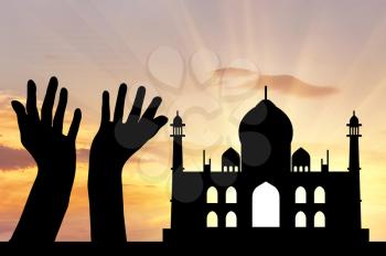 Concept of religion is Islam. Silhouette of hands facing the sky against a background of the evening mosque