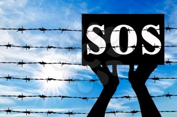 Concept of refugee. Silhouette helping hand to refugees poster which reads SOS near the fence of barbed wire