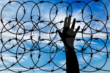 concept of the refugees. Silhouette of a hand outstretched to the sun in the sky background barbed wire