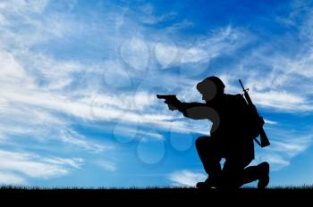 Silhouette of a soldier with a pistol on exploration on the sky background