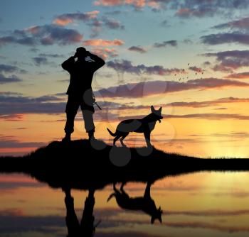 Concept of intelligence. Silhouette of a dog and a soldier looking through binoculars at sunset