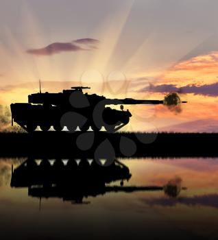 Concept of war. Silhouette of a tank with reflection on the water with a shot of the barrel shell at sunset