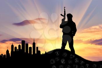 Concept of terrorism. Silhouette of a terrorist with a rifle standing on a pile of skulls on the background of evening city